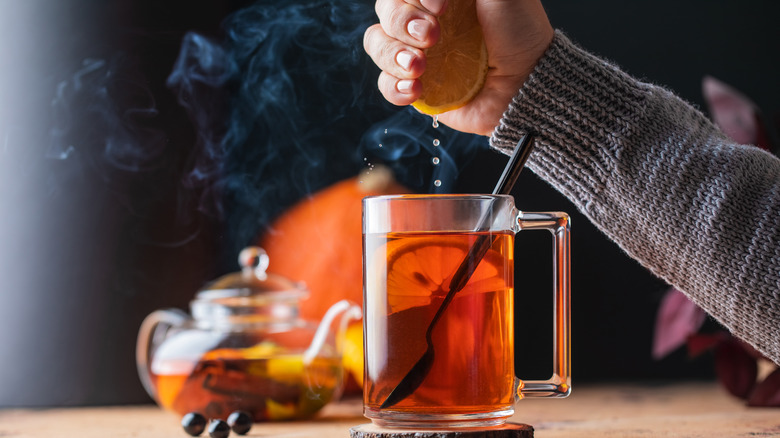 Person squeezing lemon into tea