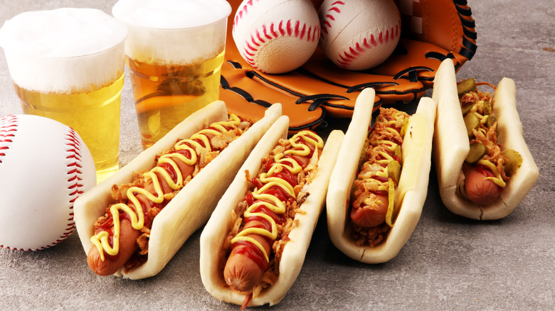 hot dogs with mustard and onions paired with beer and baseballs