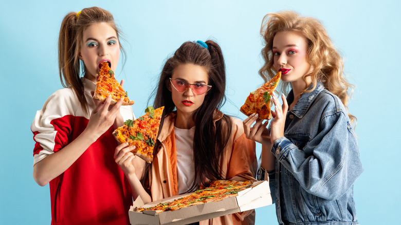 women in 90s outfits eating pizza