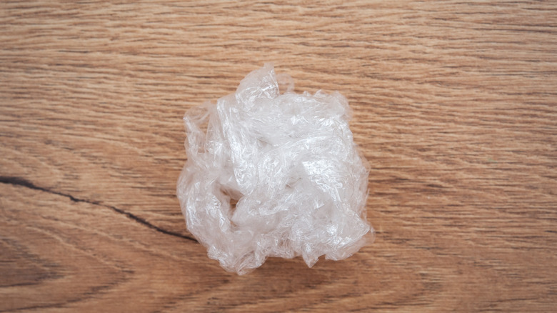 Scrunched ball of plastic film on a wooden surface