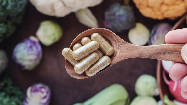 Pills on a spoon above vegetables