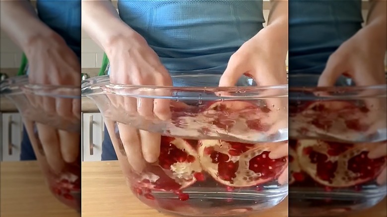 Emptying pomegranate seeds into a bowl of water