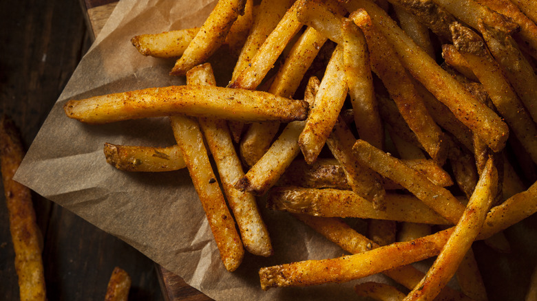 Seasoned french fries on a wooden board