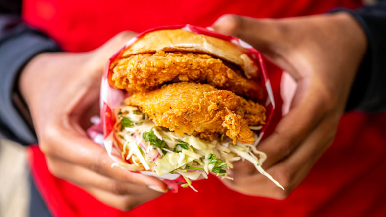 person holding a fried chicken sandwich