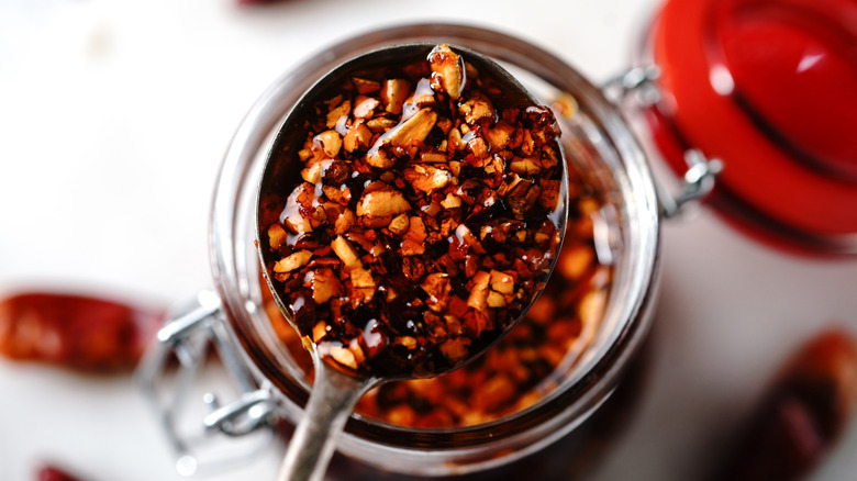 close up of a spoon holding chili crisp over its jar