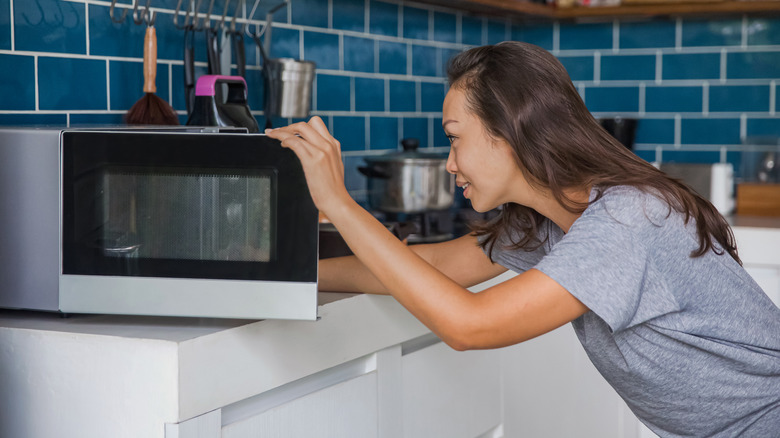 woman looking into microwave