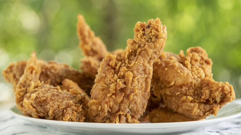 A plate of crispy fried chicken with greenery in background