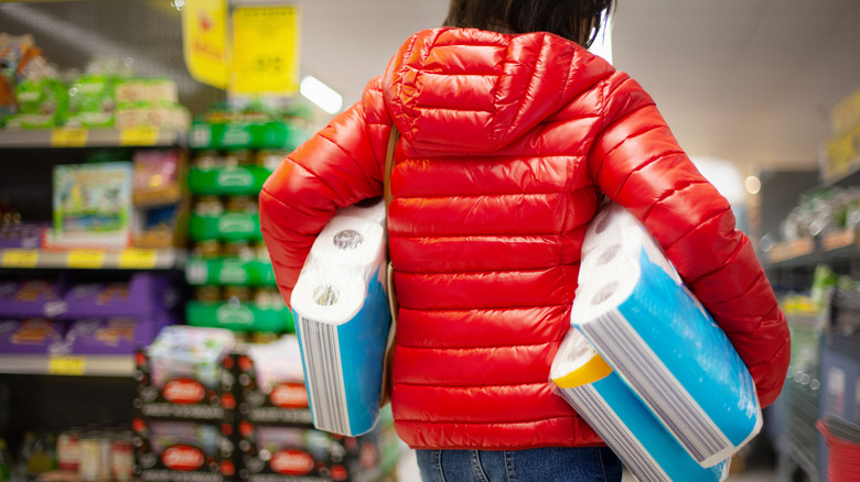 Person holding three packages of toilet paper at the store