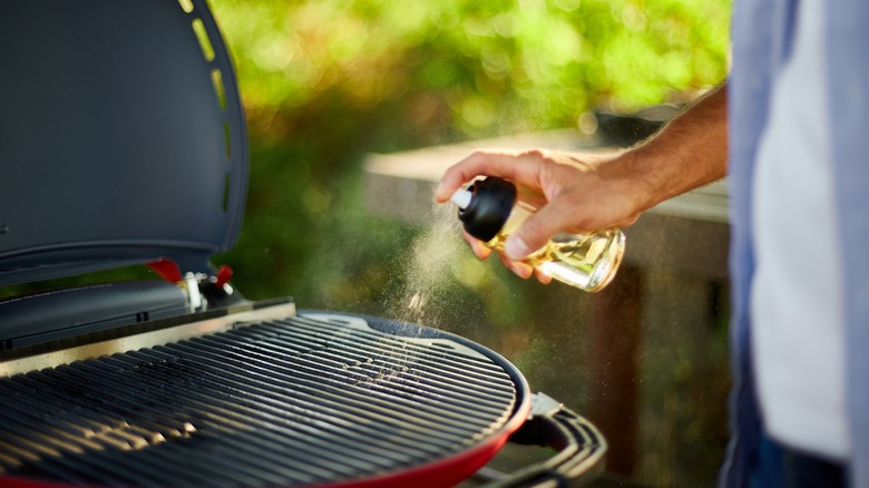 hand spraying oil on grill