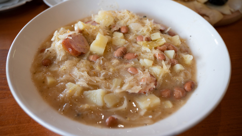 White beans and sauerkraut stew in white bowl on wooden table