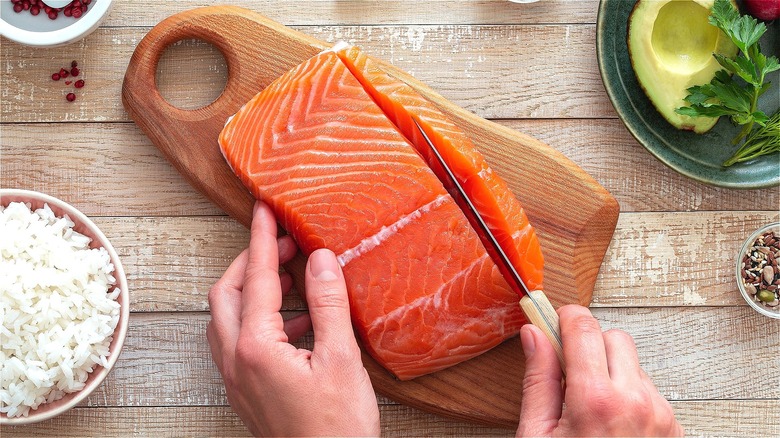 Knife cutting into raw salmon