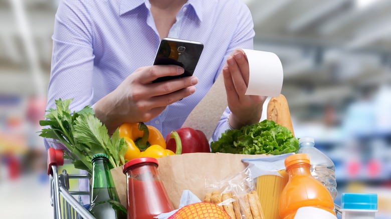 woman calculating grocery bill with a smartphone