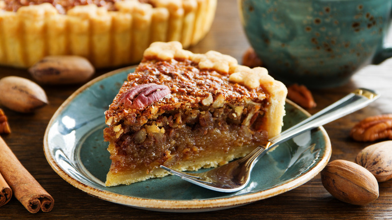 A thick slice of pecan pie on a blue plate with a fork