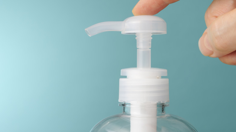 hand pushing soap bottle dispenser