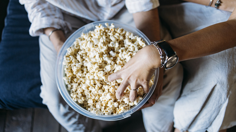 Person reaching into bowl of popcorn