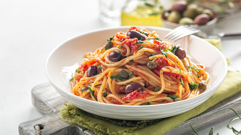 a bowl of tomato pasta with olives