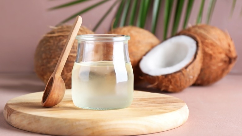 Coconut oil in a jar with coconuts in background