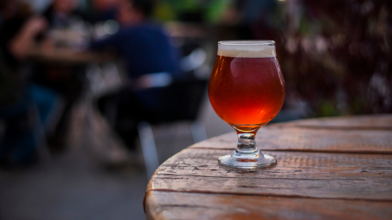 Amber beer in tulip glass on outdoor wooden table