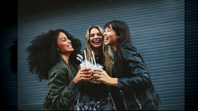 Three women holding iced coffees