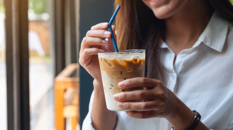 A woman holds an iced coffee