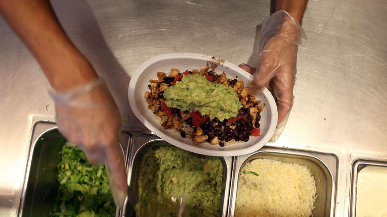 Chipotle employee preparing bowl with guacamole