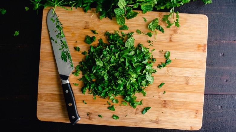 parsley and mint chopped on cutting board with knife