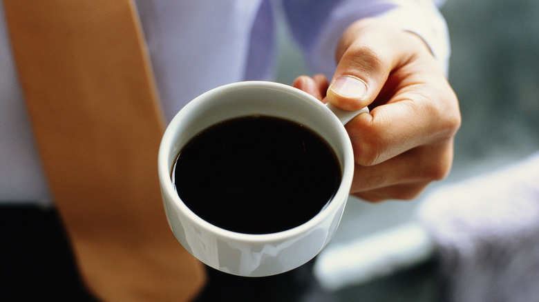 man holding a cup of black coffee