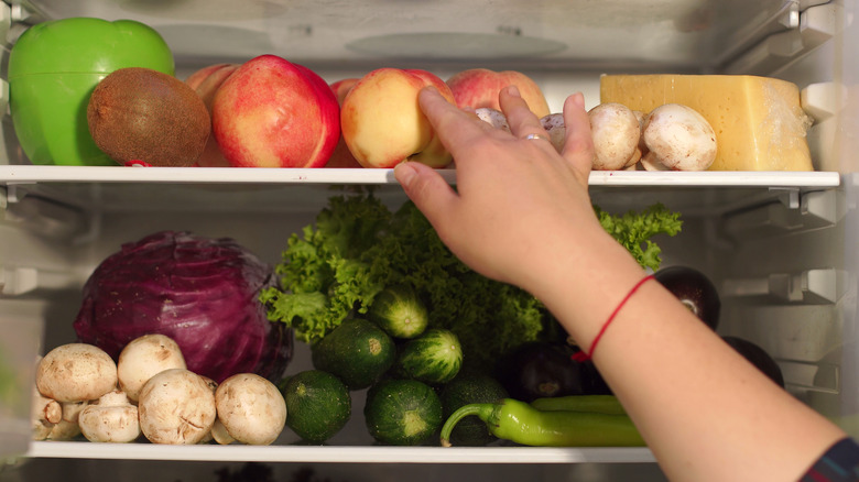 woman reaching for refrigerated peaches