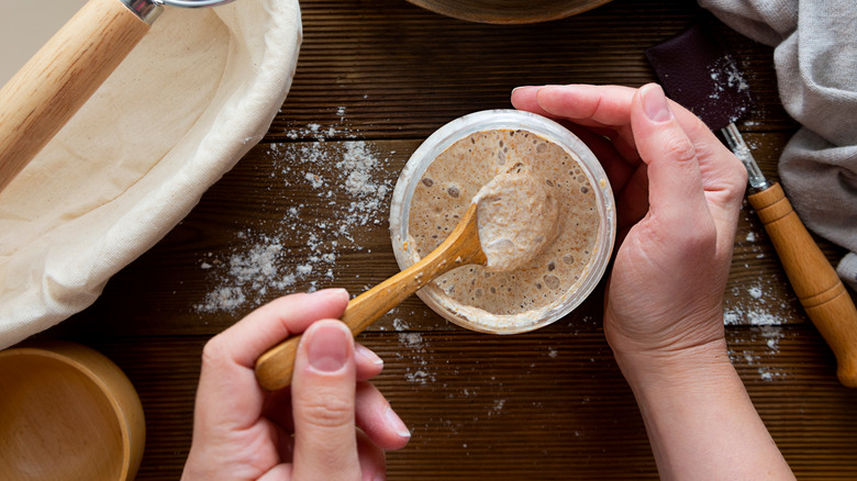 person mixing sourdough starter in a jar