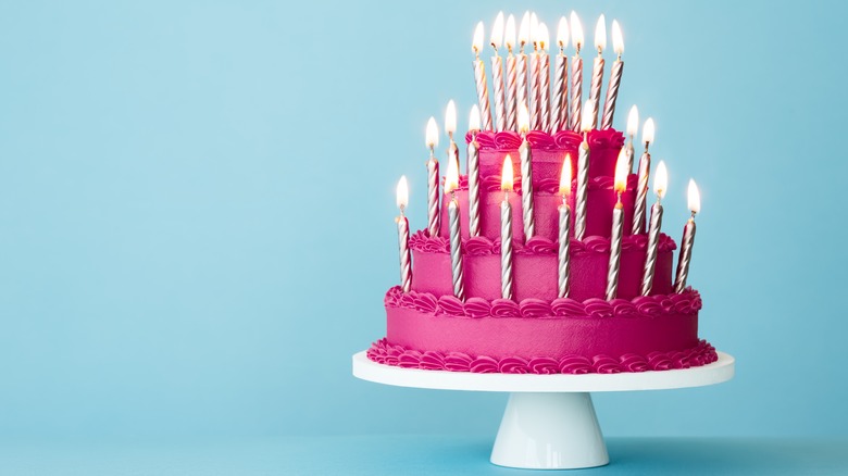 hot pink tiered cake with candles 