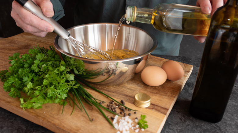 whisking salad dressing in bowl on cutting board