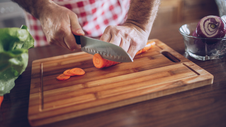 hands cutting carrots on cutting board