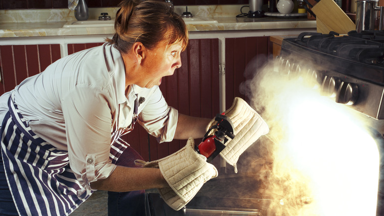 Woman putting out oven fire