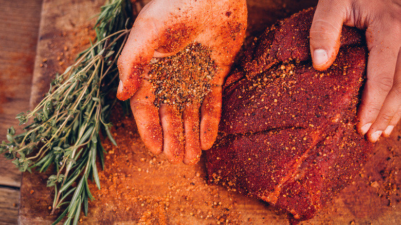 Hand putting spices on steak