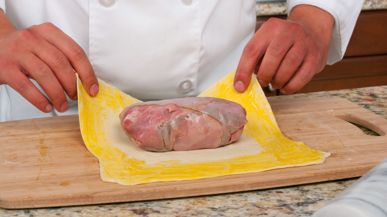 chef wrapping beef wellington in puff pastry