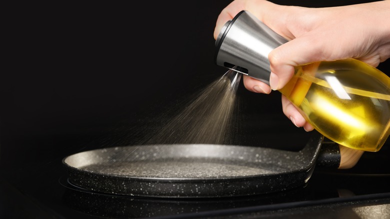 Person using cooking spray on pan