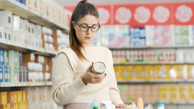 A woman reading a food label on a can