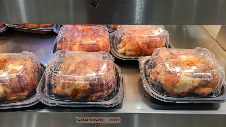 Rotisserie chickens in packaging under heat lamp