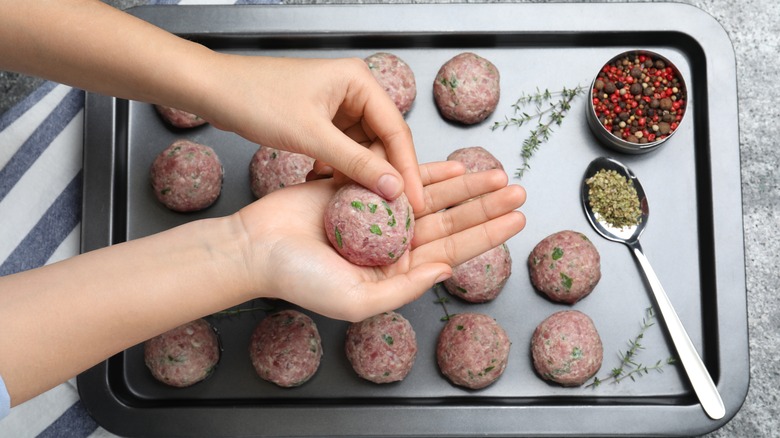 Hands forming meatballs on sheet