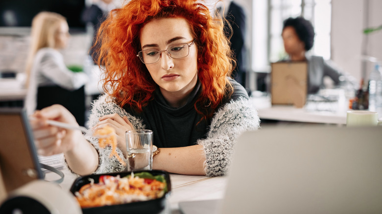 Red-haired woman unhappily looking at her meal