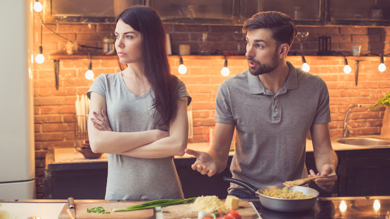 Young couple arguing while cooking dinner