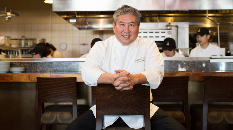 Chef Alan Wong in a chair smiling