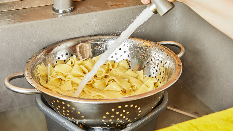 Person rinsing pasta in the sink