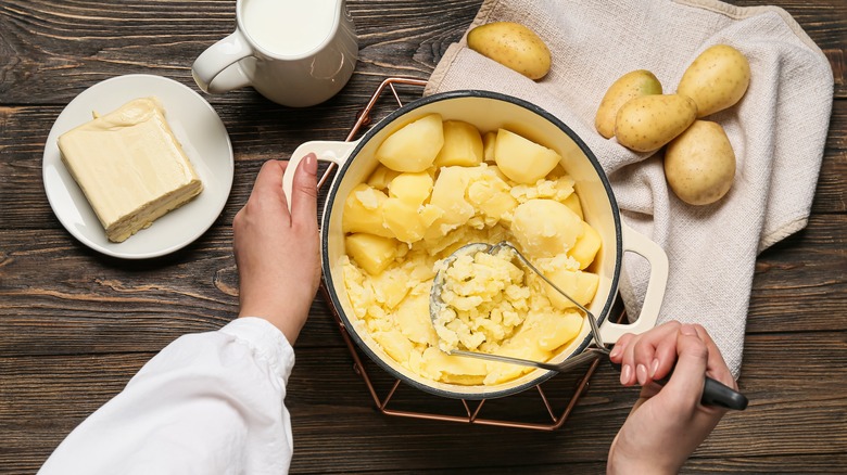 Person mashing potatoes in pot