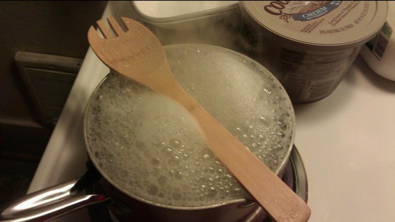 wooden spoon over boiling pot