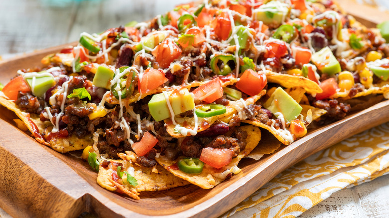 Loaded nachos on a wooden serving tray