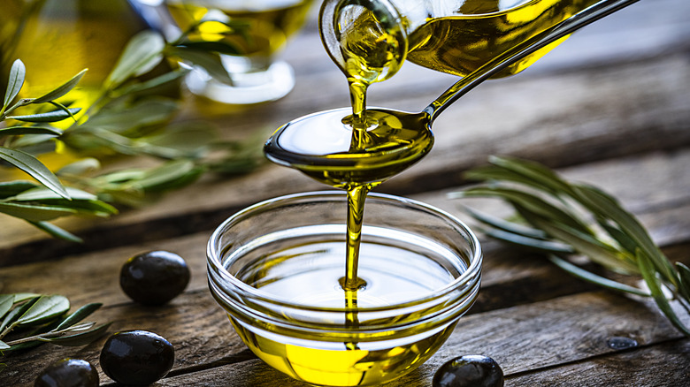 Pouring olive oil into a glass dish over a spoon