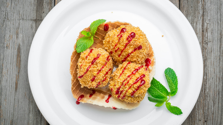 three balls of fried ice cream with fruit sauce on top