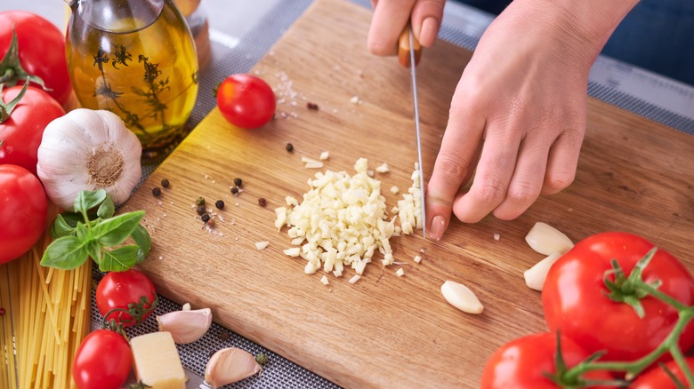 Garlic being chopped on cutting board