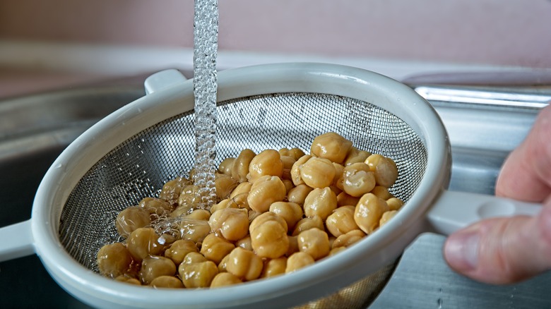 person rinsing cooked chickpeas under water